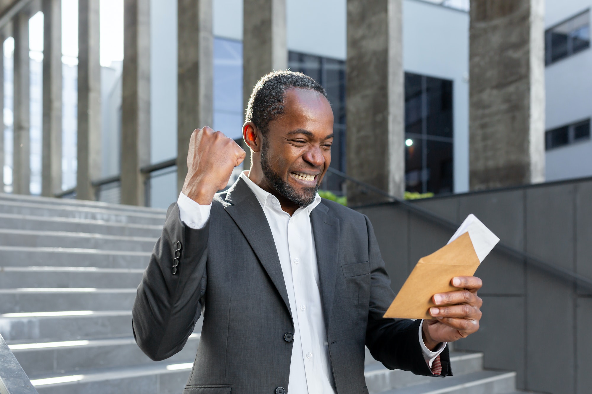 Happy african american businessman received good news news letter, boss in business suit reading